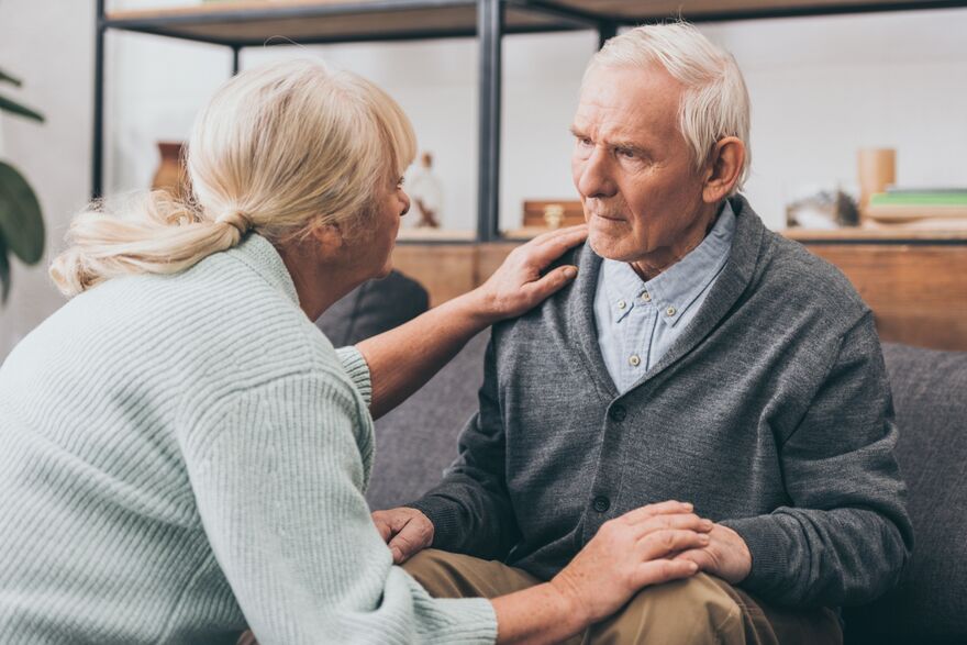retired couple holding hands and looking at each other at home