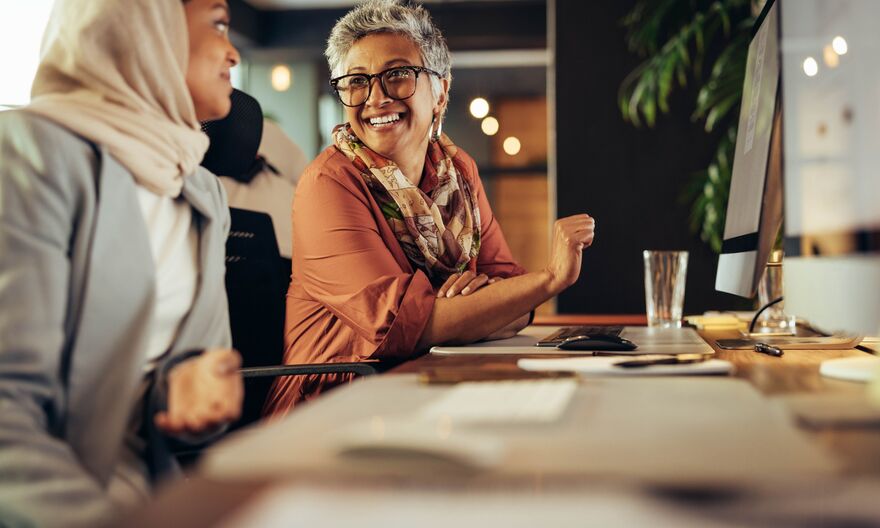To women in front of a computer screen smiling
