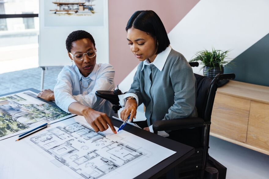 Two young women discussing architectural blueprints in a modern office