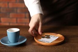 Waitress taking tips from wooden table in cafe, closeup