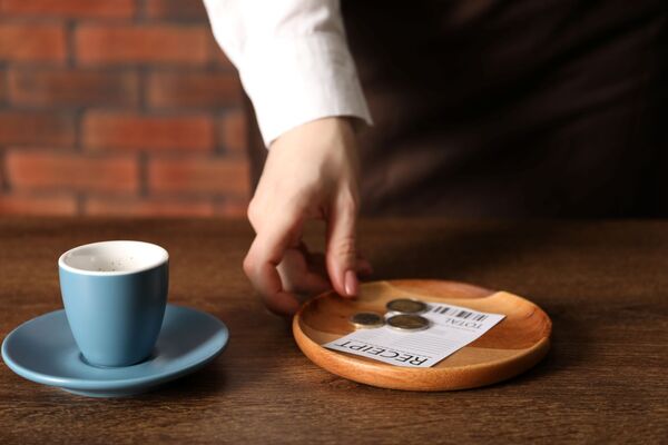 Waitress taking tips from wooden table in cafe, closeup