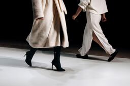 Cropped figures of fashion models women wearing white outfits on a runway