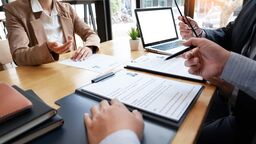 a woman sitting at a desk in a meeting with two men