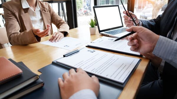 a woman sitting at a desk in a meeting with two men