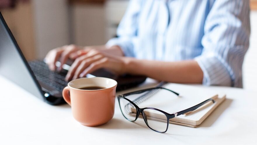 Woman working from home with laptop and coffee