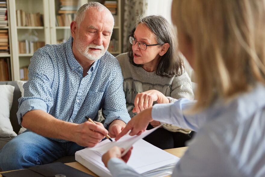 older man signing paperwork with him family