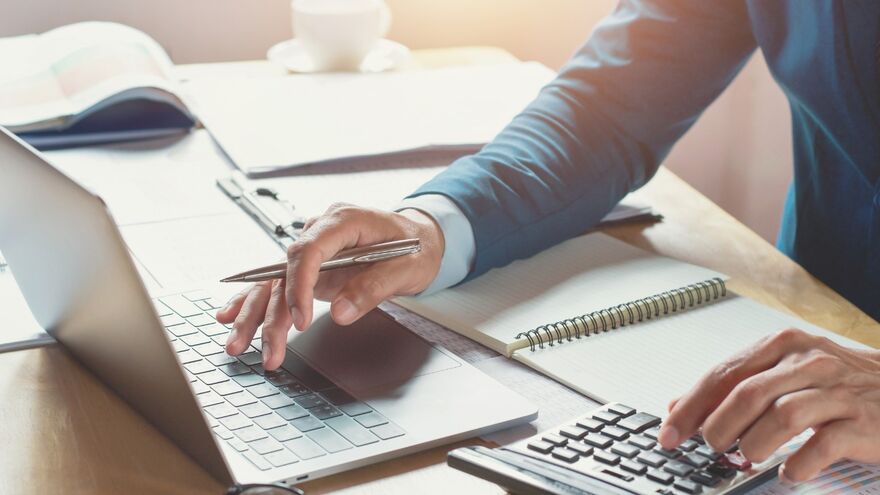 Person at table with calculator and computer