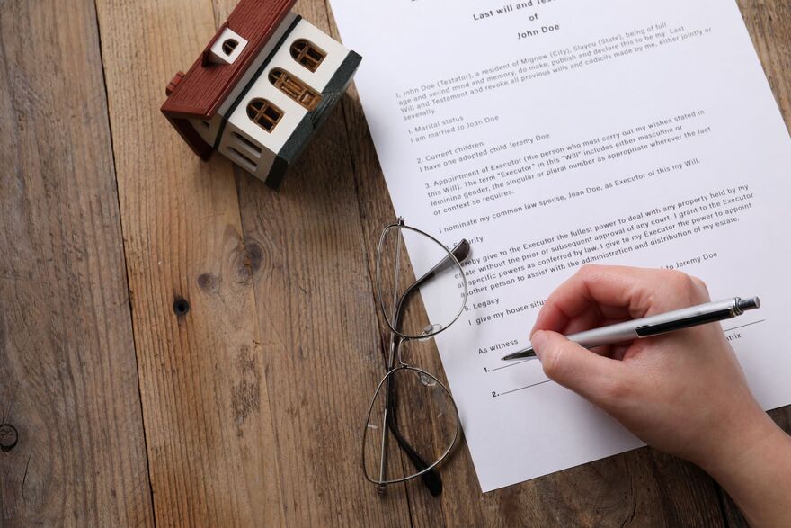 Woman signing Last Will and Testament at wooden table