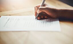 close up of hand filling in paperwork