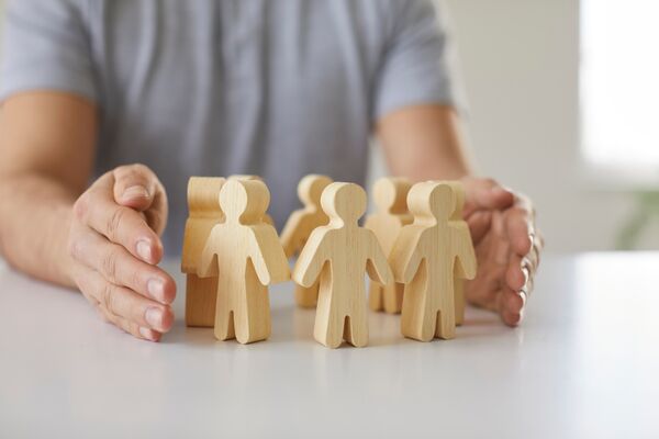 Man guarding small wooden people with hands