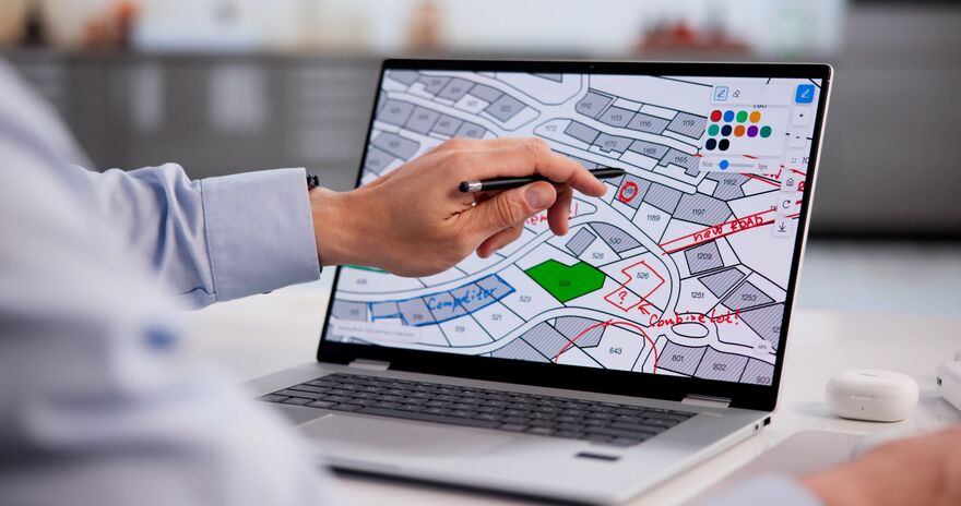man pointing at laptop screen which shows plots of land being developed for housing 