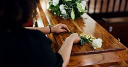 Hands, woman and rose at funeral for farewell, mourning death and goodbye at burial ceremony