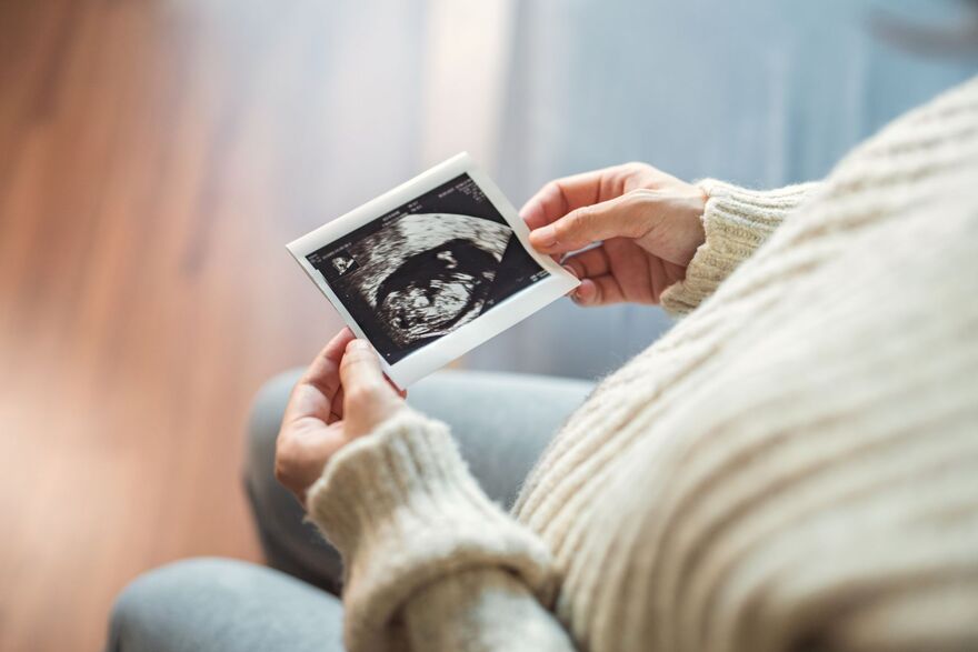Close-up - Hand of happy pregnant woman watching her ultrasound report