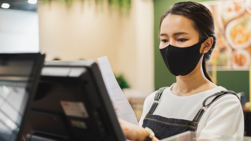 Woman at till wearing face covering