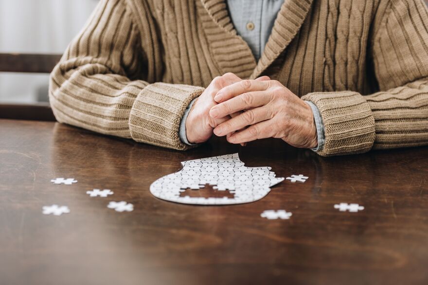 cropped view of retired man playing with puzzles on table