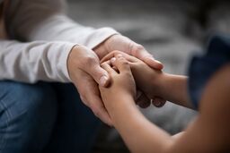 Adult holding child hands